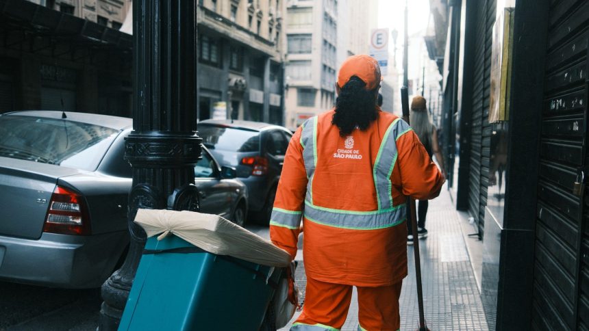 Trabalhador da limpeza urbana carrega equipamentos em uma rua de São Paulo.