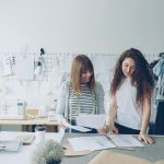Duas mulheres trabalham no desenvolvimento de roupas em um estúdio moderno de moda.