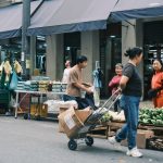 Consumidores circulam por uma feira livre em São Paulo entre barracas de hortaliças e outros produtos.