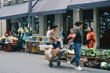 Consumidores circulam por uma feira livre em São Paulo entre barracas de hortaliças e outros produtos.