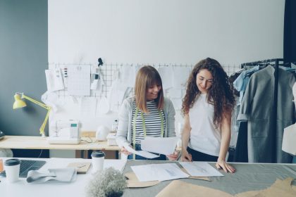 Duas mulheres trabalham no desenvolvimento de roupas em um estúdio moderno de moda.