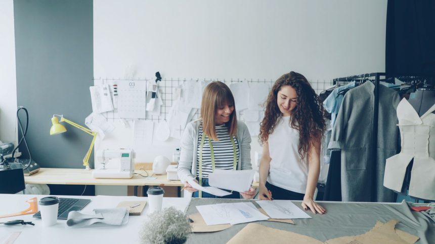 Duas mulheres trabalham no desenvolvimento de roupas em um estúdio moderno de moda.