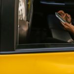Passageiro usa um smartphone no banco traseiro de um táxi durante uma viagem.