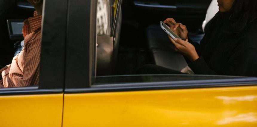 Passageiro usa um smartphone no banco traseiro de um táxi durante uma viagem.