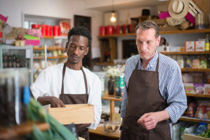 Dois funcionários organizam produtos nas prateleiras de um supermercado.